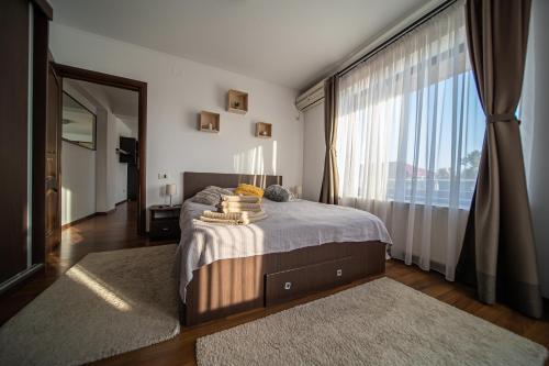 a bedroom with a bed with a large window at Apartament Tatu bar&grill in Otopeni