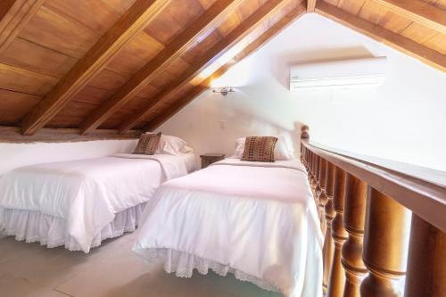 two beds in a attic room with wooden ceilings at Hotel Casa La Fe in Cartagena de Indias