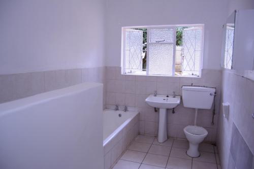 uma casa de banho com um lavatório e um WC. em Royal Guest House em Harare