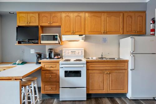 a kitchen with wooden cabinets and white appliances at Tiki Shores Inn & Suites in Penticton