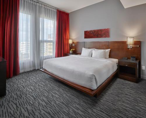 a large bed in a hotel room with red curtains at Matrix Hotel in Edmonton