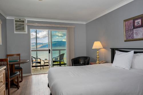 a hotel room with a bed and a view of the ocean at Tiki Shores Inn & Suites in Penticton
