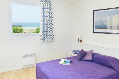 a purple bed in a white room with a window at Résidence Néméa Kermael in Saint-Briac-sur-Mer