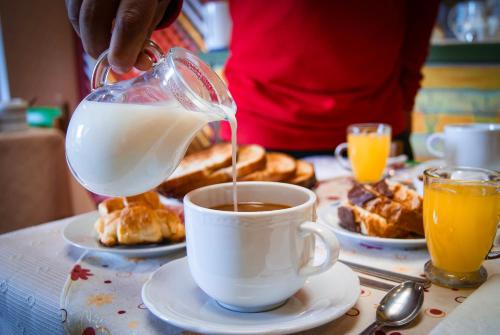 a person is pouring milk into a cup of coffee at Hospedaje Flores del Sur in El Calafate