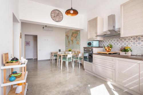 una cucina con armadi bianchi, tavolo e sedie di 40° Parallelo Guest House a Riola Sardo