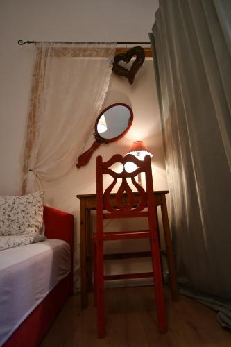 a table with a mirror and a chair next to a bed at Tulipán Villa Panzió in Szolnok