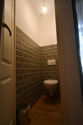 a bathroom with a toilet and a brick wall at Tulipán Villa Panzió in Szolnok