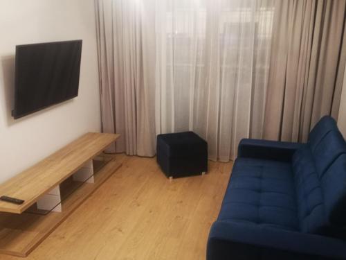 sala de estar con sofá azul y TV en Apartament Przy Galerii, en Radom