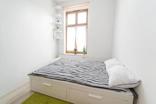 Una cama en una habitación blanca con ventana. en Apartament Copernicus Olsztyn, en Olsztyn