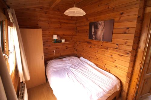 una piccola camera con un letto su una parete in legno di Chaletparc Krabbenkreek Zeeland - Chalet 130 a Sint Annaland