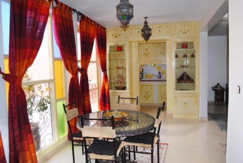 d'une salle à manger avec une table, des chaises et une fenêtre. dans l'établissement Appartement Anatim, à Ouarzazate