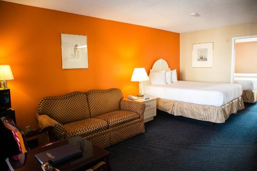 um quarto de hotel com uma cama e um sofá em Anaheim Carriage Inn em Anaheim