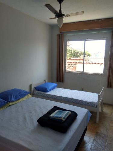 two beds in a room with a window at Sollarium GINI Suítes in Guarapari