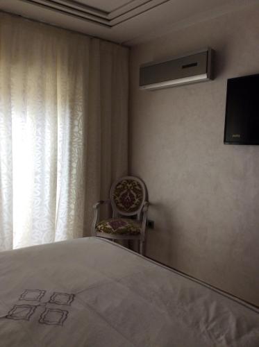 una camera con un letto e una sedia e una finestra di Appartement de luxe a Casablanca