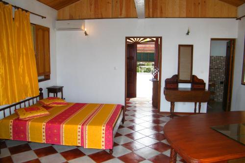 1 dormitorio con cama, mesa y piano en Villa de charme avec piscine MQAA07, en Les Anses-dʼArlet