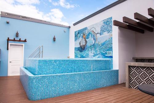 a mural on the wall of a room with blue tiles at Casa Barco Hotel Boutique in Isla Mujeres