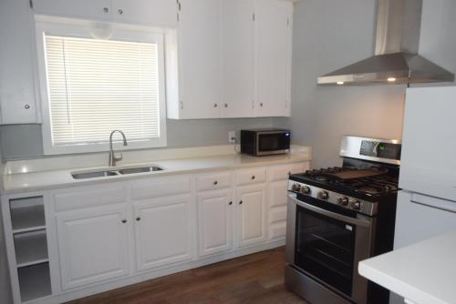 a kitchen with white cabinets and a sink and a microwave at Dahl's Motel in Oroville
