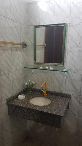 een badkamerbar met een wastafel en een spiegel bij Pousada Siroba Beira Rio in Morretes