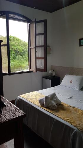 a bedroom with a bed with two pairs of shoes on it at Pousada Siroba BEIRA RIO in Morretes