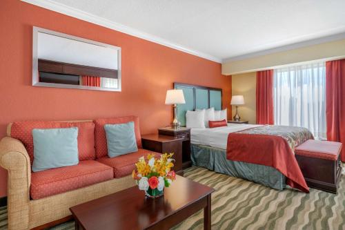 パームビーチ・ガーデンズにあるBest Western Plus Palm Beach Gardens Hotel & Suites and Conference Ctのベッドとソファのあるホテルの部屋