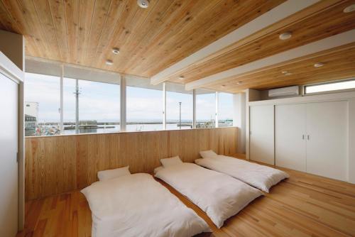 Bett in einem Zimmer mit einem großen Fenster in der Unterkunft 渚泊魚津丸 in Motoshin