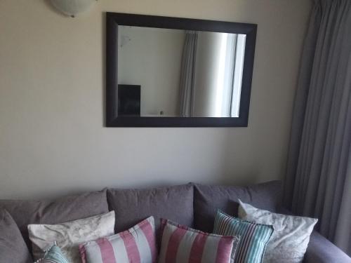 a mirror on the wall above a couch with pillows at Sunset 786 Holidays 211 in Strand