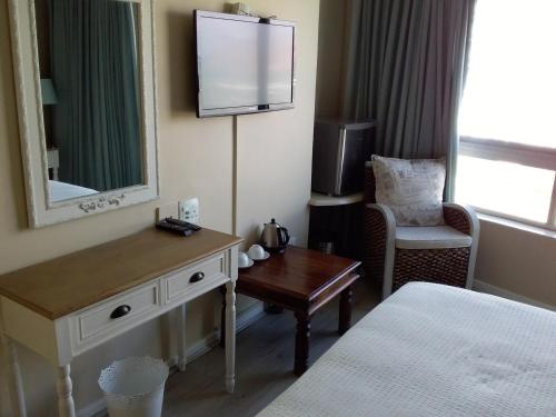 Cette chambre comprend un lit, un bureau et une télévision. dans l'établissement Sunset 786 Holiday Accom-212, à Strand