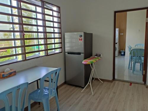 a kitchen with a refrigerator and a table and chairs at Penginapan The CityScape - Cukup Rehat & Tidur Lena Hingga Pagi in Lumut