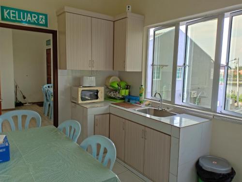 a kitchen with a sink and a table with chairs at Pusat Penginapan The CityScape - Cukup Rehat & Lena Hingga Pagi in Lumut