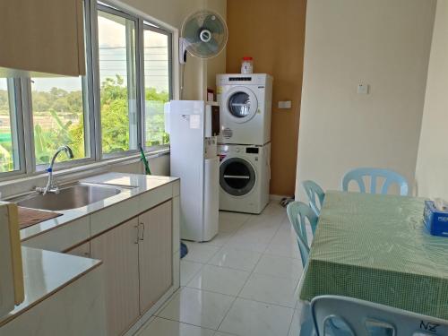 a kitchen with a refrigerator and a washing machine at Penginapan The CityScape - Cukup Rehat & Tidur Lena Hingga Pagi in Lumut