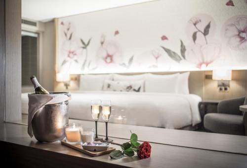 Sivatel Bangkok Hotel في بانكوك: غرفة بسرير وطاولة مع زجاجة من النبيذ والشموع