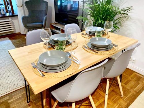 a wooden table with chairs and plates and wine glasses at Old Town Apartment-City Centre in Warsaw