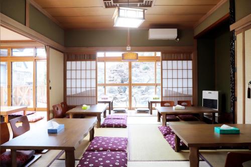 un comedor con mesas, bancos y ventanas en Plum House Otaru, en Otaru