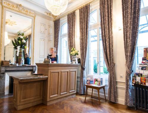 a salon with a fireplace in a room with windows at Hôtel Spa Marotte in Amiens