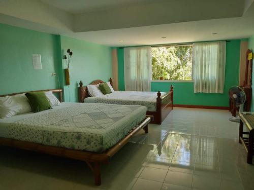 een slaapkamer met 2 bedden en een raam bij Green Home in Khao Lak