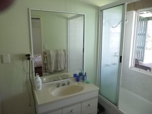 a bathroom with a sink and a shower with a mirror at dad & alice's place in Tin Can Bay