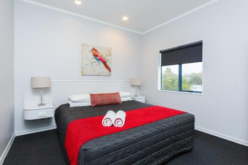 a bedroom with a bed with two flip flops on it at Aubyn Court Spa Motel in Palmerston North