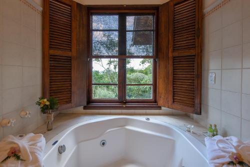 a bath tub in a bathroom with a window at Quinta dos Pinhais Pouso e Charme in Santo Antônio do Pinhal