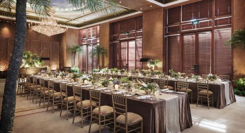 a long table with chairs in a room with windows at The Dharmawangsa Jakarta in Jakarta
