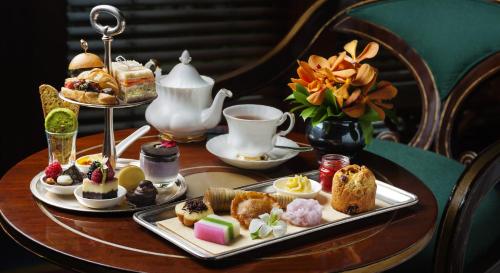 a table with a tray of pastries and a tea set at The Dharmawangsa Jakarta in Jakarta