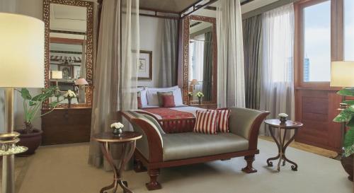 a bedroom with a bed and a chair and a mirror at The Dharmawangsa Jakarta in Jakarta