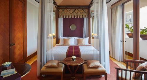 a hotel room with a bed and a table and chairs at The Dharmawangsa Jakarta in Jakarta