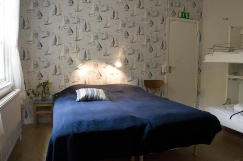 a bedroom with a bed with a blue blanket and a wall with sails at Hasselö Hostel in Hasselö