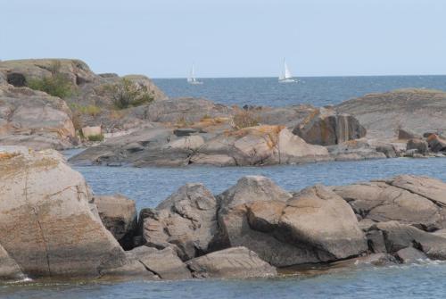 a group of rocks in the water with boats in the water at Hasselö Hostel in Hasselö