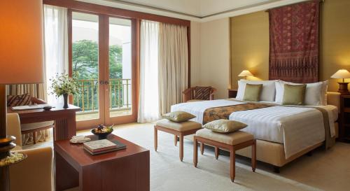 a hotel room with a large bed and a balcony at The Dharmawangsa Jakarta in Jakarta