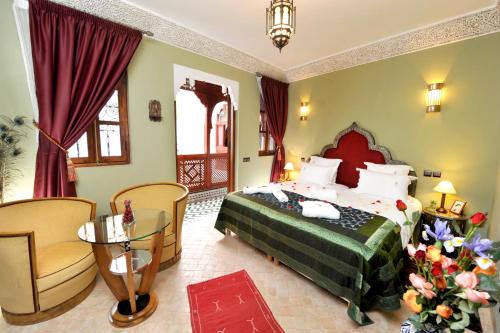 a bedroom with a bed and a chair and a table at Riad Belle Epoque in Marrakesh