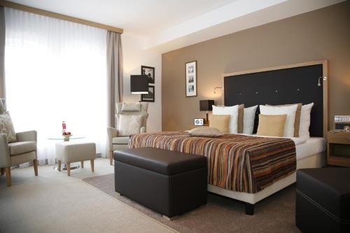 um quarto de hotel com uma cama grande e uma cadeira em Hotelpark Stadtbrauerei Arnstadt em Arnstadt