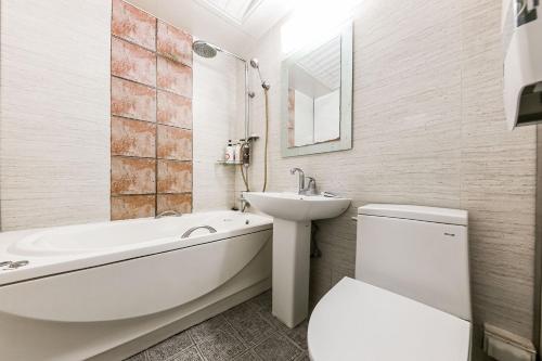 baño blanco con lavabo, bañera y aseo en Manhattan Hotel en Cheongju