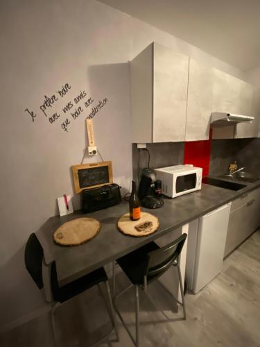 a small kitchen with a counter with a microwave and a table at Le Belvédère - GÎTES MARCK in Turckheim