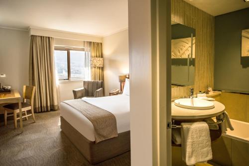 a hotel room with a bed and a sink and a tub at Garden Court Eastgate in Johannesburg